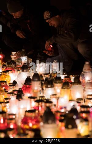 Zwei Männer stellen Kerzen vor dem Denkmal für die polnischen Opfer des Kommunismus auf dem Rakowicki-Friedhof in Krakau, Polen 2019. Stockfoto