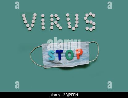 VIRUS STOP Inschrift aus weißen Pillen auf schwarzem Hintergrund mit einer medizinischen Maske Stockfoto