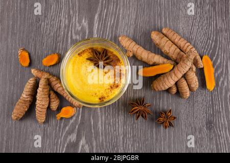 Traditionelles indisches Getränk Kurkuma Latte oder goldene Milch mit Zimt, Ingwer, Anis, Pfeffer und Kurkuma. Draufsicht. Stockfoto