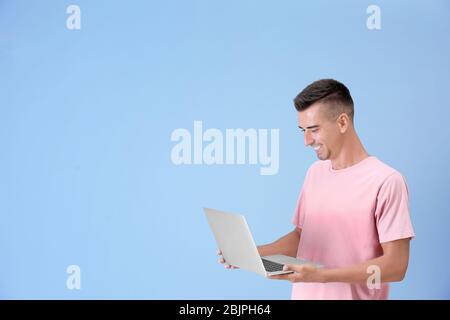 Junger Mann mit Laptop auf farbigen Hintergrund Stockfoto