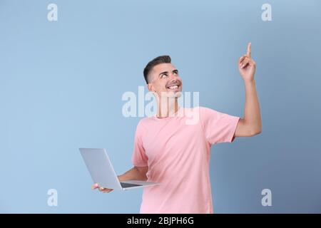 Emotional junger Mann mit Laptop auf farbigen Hintergrund Stockfoto
