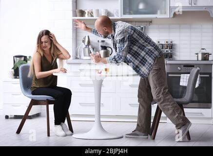 Junger Mann mit einer Flasche Alkohol missbraucht Frau in der Küche Stockfoto