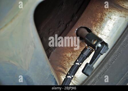 Nahaufnahme eines tragbaren Luftkompressors, der mit dem Ventilschaft eines Autoreifens verbunden ist Stockfoto