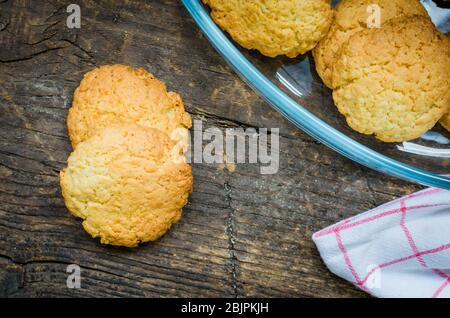 Hausgemachte Kokosnusskekse auf einem dunklen alten Holztisch. Frisch gebackene Kokosnusskeks auf rustikalem Hintergrund. Draufsicht. Stockfoto