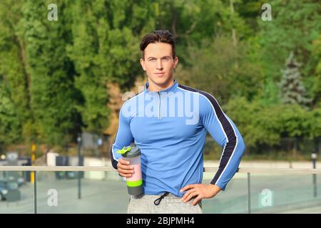 Sportlicher junger Mann mit Proteinshake, im Freien Stockfoto