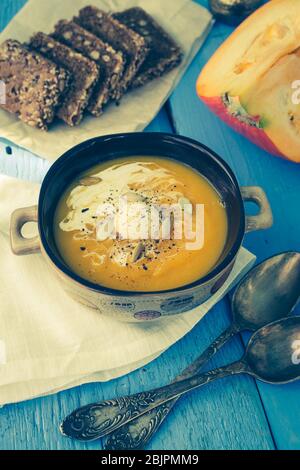 Kürbissuppe mit Sahne, Käse und Kürbiskernen auf blauem Holzhintergrund. Kürbissuppe mit frischen Kürbissen. Halloween Thanksgiving Herbst Essen Gemeinsame Lizenz Stockfoto