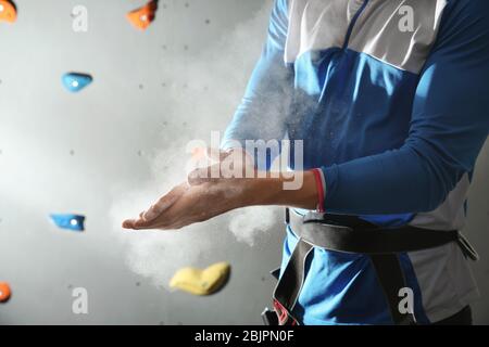 Junger Mann, der Talkpulver auf die Hände in der Kletterhalle anwendet Stockfoto