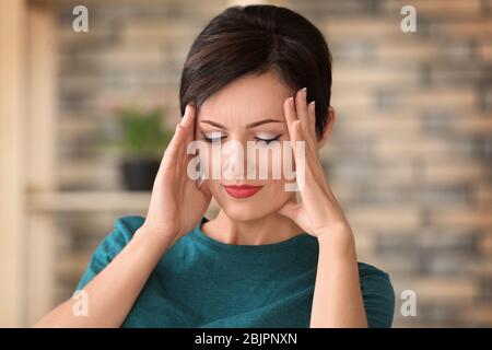 Schöne reife Frau, die zu Hause an Kopfschmerzen leidet Stockfoto