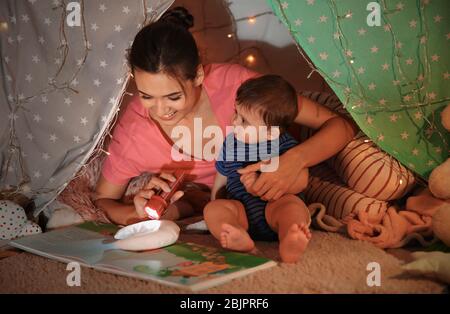 Junge Mutter mit kleinen Sohn Lesebuch in hovel zu Hause Stockfoto