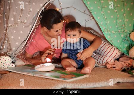 Junge Mutter mit kleinen Sohn Lesebuch in hovel zu Hause Stockfoto