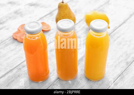 Flaschen mit Obst und Gemüsesäften auf Holztisch Stockfoto