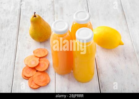 Flaschen mit Obst und Gemüsesäften auf Holztisch Stockfoto