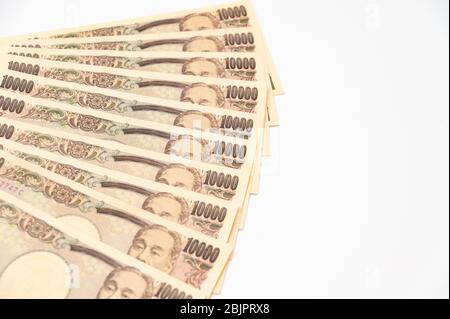 100,000 Yen in Schichten von 10,000 Yen Banknoten gestapelt. Isoliert auf weißem Hintergrund. Kopierbereich. Horizontale Aufnahme. Stockfoto