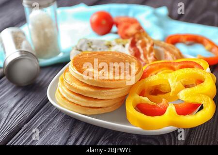 Teller mit leckeren Pfannkuchen und Speck auf Holztisch Stockfoto