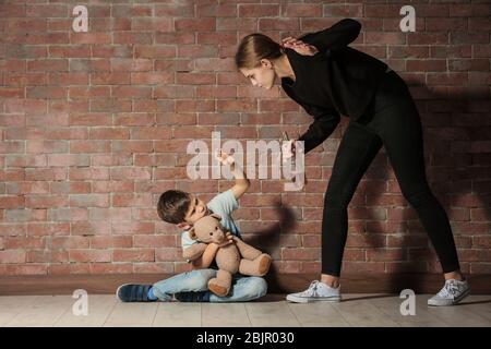 Betrunkene Frau, die ihren Sohn gegen eine Mauer bedroht Stockfoto