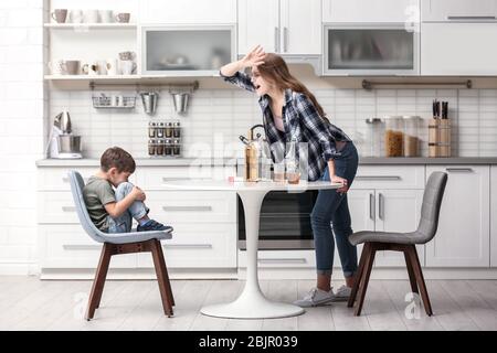 Betrunkene Frau bedroht ihren Sohn in der Küche Stockfoto