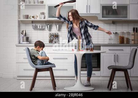 Betrunkene Frau bedroht ihren Sohn in der Küche Stockfoto