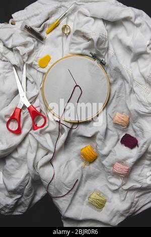 Nahaufnahme von Stickwerkzeugen, Stricken, Nähen, Handarbeit Hobby. Schere, Nadel, Faden, Stickrahmen Stockfoto