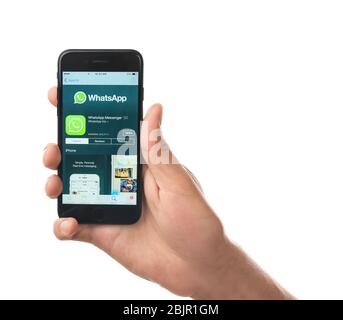KIEW, UKRAINE - 17. OKTOBER 2017: Mann mit iPhone 7 Black und WhatsApp-Symbol im App Store auf dem Bildschirm vor weißem Hintergrund Stockfoto