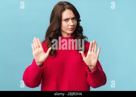 Foto von kaukasischen ernste Frau mit langen braunen Haaren tun Stop oder Verleugnung Geste isoliert über blauen Hintergrund Stockfoto