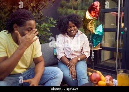 Afroamerikanischer Mann und Frau sitzen im Hinterhof, reden, lächeln, lachen, sich unterhalten Stockfoto