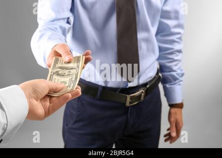 Frau, die Geld an den Mann auf hellem Hintergrund gibt Stockfoto