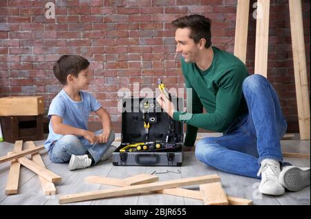 Vater zeigt seinem kleinen Sohn verschiedene Werkzeuge in der Werkstatt Stockfoto