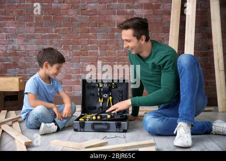 Vater zeigt seinem kleinen Sohn verschiedene Werkzeuge in der Werkstatt Stockfoto