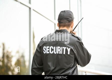 Männlicher Wachmann mit tragbarem Funksender in der Nähe des Gebäudes im Freien Stockfoto