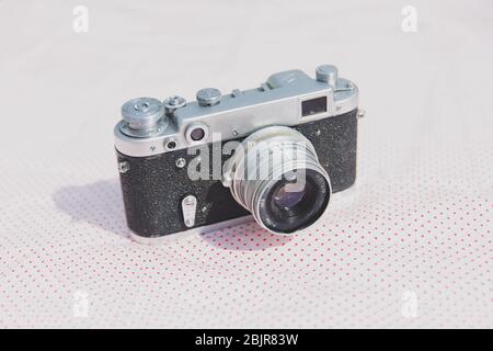 Vintage-Kamera auf rot gepunktetem Hintergrund und Sonnenlicht, Sommerurlaubserinnerungen, Filmfotografie Stockfoto