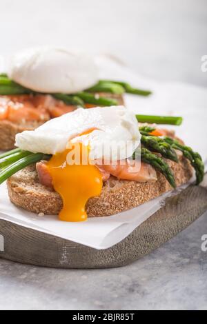 Gesundes vegetarisches Gericht. Toast, pochiertes Ei, Spargel, Lachsfisch. Steinhintergrund. Saubere Ernährung Ernährung. Bio-Lebensmittel. Stockfoto