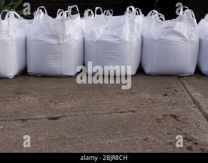 Reihe von weißen Plastiksandsäcken mit Beton im Vordergrund Stockfoto