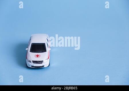 Ambulance Car auf blauem Hintergrund. Ein medizinischer Notdienst. Spielzeug Medizinisches Fahrzeugmodell. Stockfoto