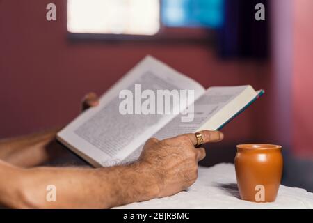 Mann liest Buch zu Hause, um zu vermeiden, dass sich Corona-Virus ausbreitet. Konzept für zu Hause bleiben Leben retten, selbst-Quarantäne, Coronavirus-Prävention, soziale Distanzierung Stockfoto