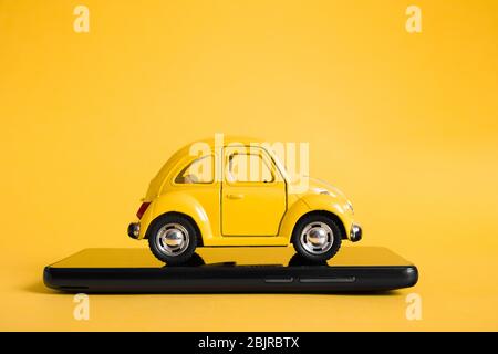 Urban Taxi mobile Online-Anwendung Konzept. Spielzeug gelb Taxi Auto Modell. Smartphone mit Hand und Taxi-Service-App auf dem Display. Modell mit Kopie Stockfoto