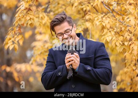 Junger schöner Mann mit Taube im Park Stockfoto