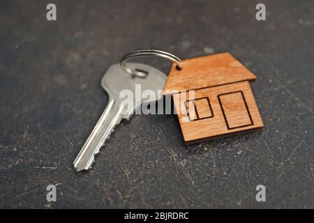 Schlüssel mit Schmuckkästchen in Form eines Hauses auf einem dunklen Tisch Stockfoto