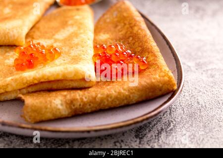 Traditionelle russische Pfannkuchen mit rotem Kaviar. Gebratene Crepes mit Kaviar und saurer Sahne Stockfoto