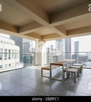 Obere Außenterrasse mit Tisch, Sitzgelegenheiten und Blick auf die Stadt. 25 Cabot Square, London, Großbritannien. Architekt: Carmody Groarke, 2019. Stockfoto