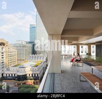 Obere Außenterrasse mit Garten und Blick auf 1 Canada Squaure. 25 Cabot Square, London, Großbritannien. Architekt: Carmody Groarke, 2019. Stockfoto