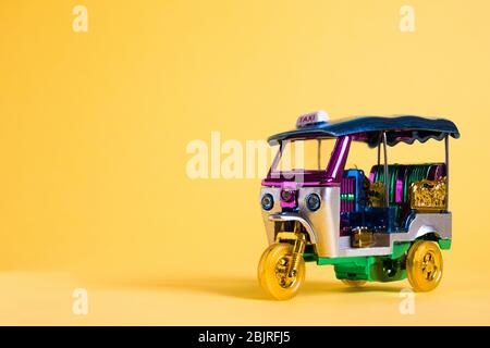 Modell Toy Tuk Tuk isoliert auf gelbem Hintergrund. Thai traditionelle Taxi in Bangkok Thailand. Souvenir Stockfoto