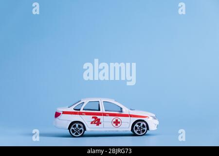 Ambulance Car auf blauem Hintergrund. Ein medizinischer Notdienst. Spielzeug Medizinisches Fahrzeugmodell. Stockfoto
