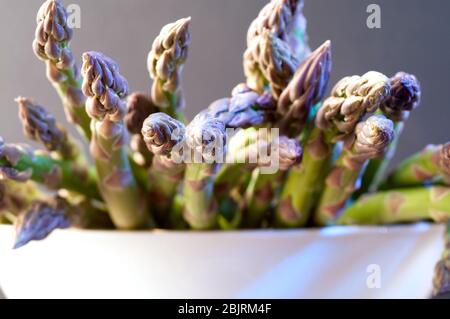 Viele Spargel auf einem Holzteller auf grauem Hintergrund. Gesunde Gemüsefutter. studio-Shoot Stockfoto