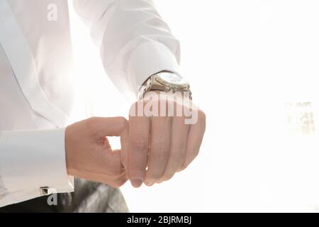 Beobachten Sie beim Anziehen am Handgelenk eines Mannes in einem weißen Hemd. Stockfoto