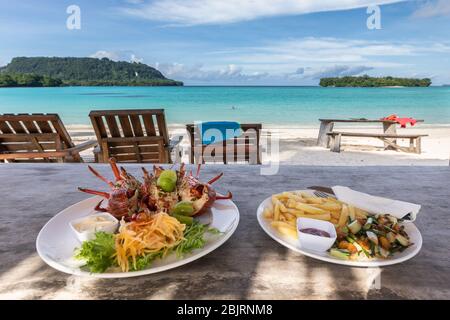 Hummer mit Pommes auf weißem Teller Strandrestaurant mit wunderschönem Blick auf die blaue Lagune des Paradieses Stockfoto