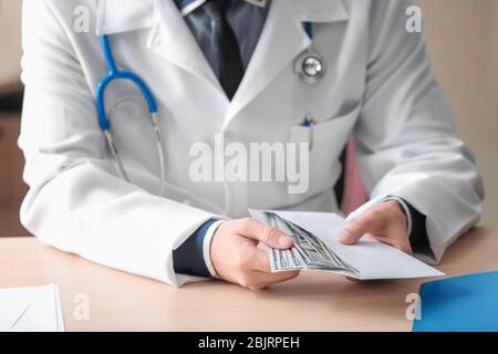 Arzt mit Geld im Umschlag am Tisch. Korruptionskonzept Stockfoto