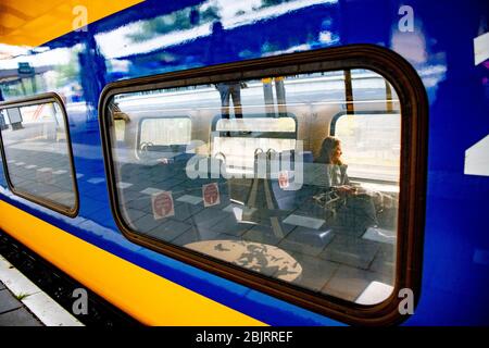 Ein Passagier auf einem Testzug der Niederländischen Eisenbahn (NS) auf der Groninger Strecke. Die NS bereitet sich auf die 1.5 Meter große soziale Distanz vor. Der Zug zeigt an, welche Sitzplätze für Reisende verfügbar sind und nicht. Ein Coupé ist auch mit Bildschirmen zwischen den Sitzen ausgestattet. Die Verkehrsbetriebe erweitern den Fahrplan erneut, da Kindern und Jugendlichen mehr Bewegungsfreiheit bei den Maßnahmen im Zusammenhang mit dem Corona-Virus eingeräumt wird. Stockfoto