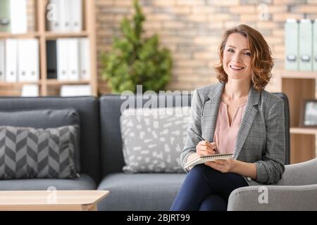 Attraktive Psychologin sitzt im Sessel im Büro Stockfoto