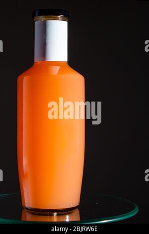 Flasche mit Orangensaft mit schwarzer Kappe auf einem Glas dunkelgrauen Hintergrund. Kopierraum, Nahaufnahme Stockfoto
