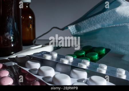 Medizinische Gläser, Thermometer, Spritze, Gaze Maske und Pillen Medikamente, Medizin auf Glas grauen Hintergrund Nahaufnahme. Copy space Stockfoto